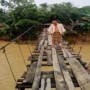 Ket : terlihat seorang warga melewat jembatan gantung yang rusak parah Desa Rantau Limau Manis (Fotografer : Aswani)